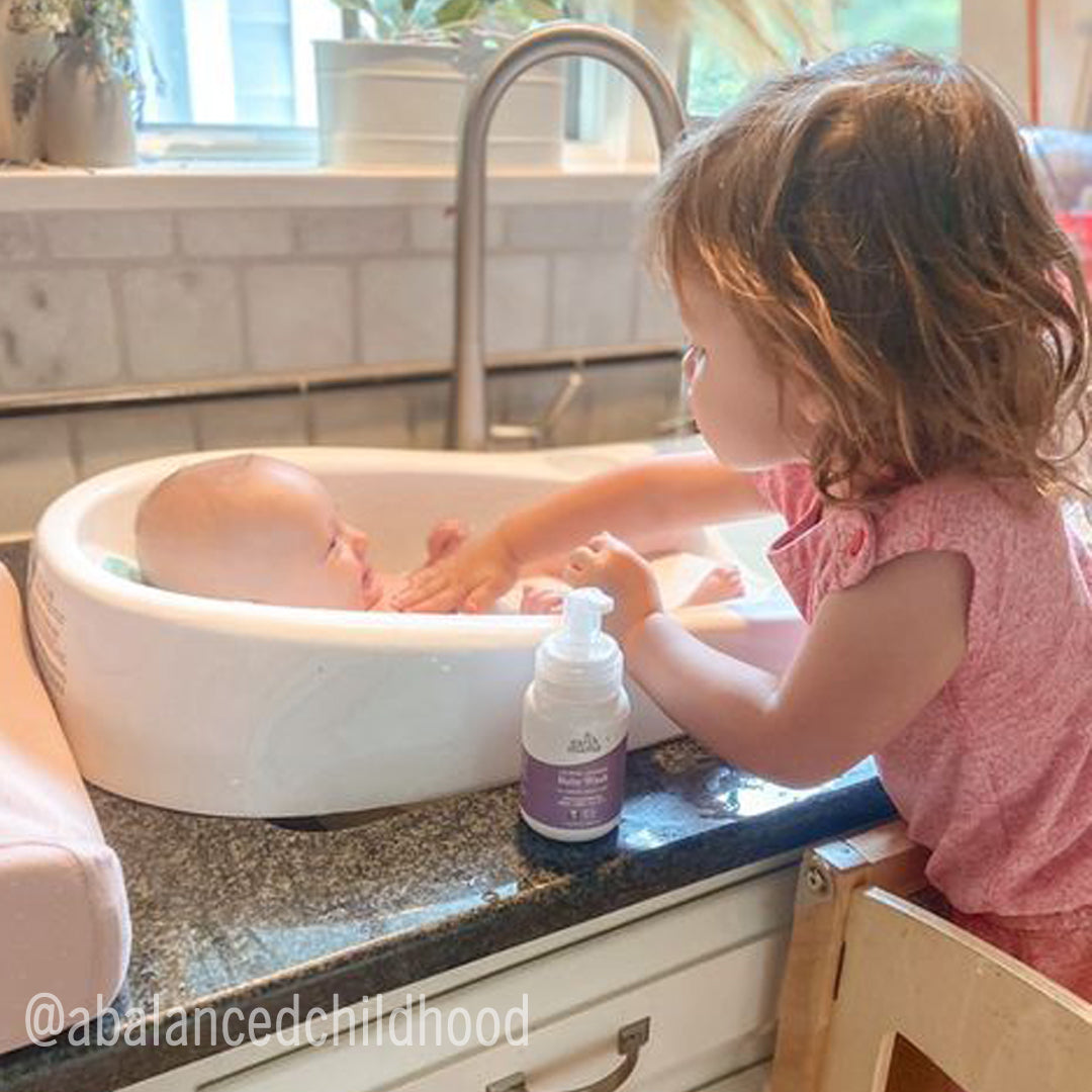 Toddler washing a baby in a sink with Castile Soap Refill, showcasing a nurturing moment.